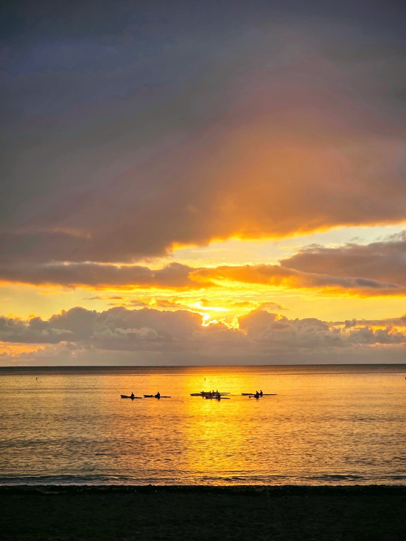 Sunset over the sea with kayakers on the water
